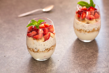 Homemade yogurt parfait with granola, strawberries, bananas and Chia seeds in glasses. Diet dessert with yogurt, Chia, muesli and fresh berries. Healthy breakfast 