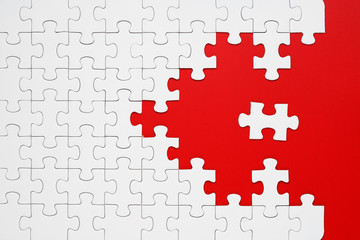 White puzzle pieces on a red background separated