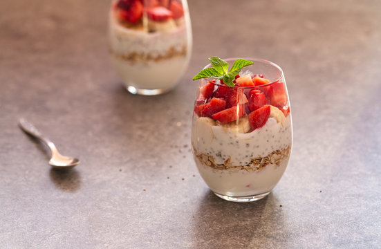 Homemade yogurt parfait with granola, strawberries, bananas and Chia seeds in glasses. Diet dessert with yogurt, Chia, muesli and fresh berries. Healthy breakfast 