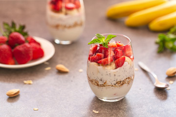 Homemade yogurt parfait with granola, strawberries, bananas and Chia seeds in glasses. Diet dessert with yogurt, Chia, muesli and fresh berries. Healthy breakfast 