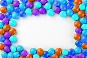 Frame of multi-colored candies close up. Rainbow colored dragee multicolored glaze on a white background