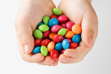 Multicolored candies in the hands of a child on a white isolated background