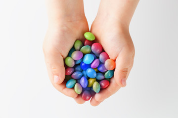Multicolored candies in the hands of a child on a white isolated background