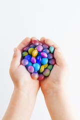 Multicolored candies in the hands of a child on a white isolated background