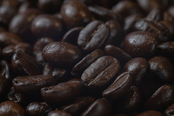 close up of pile roast coffee beans on wooden board