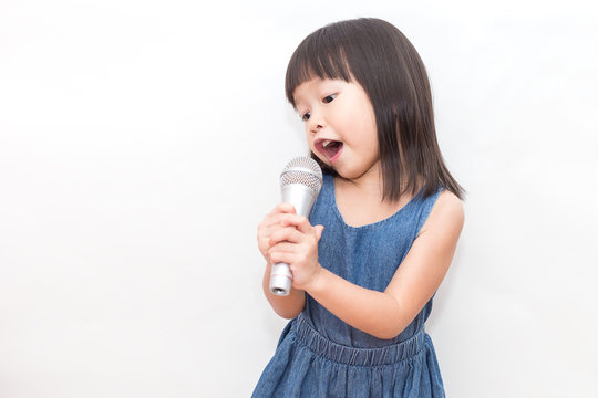 Portrait of pretty little asian toddler girl with the microphone in her hand isolated on white background, Happy fun young artist music song and early childhood education concept