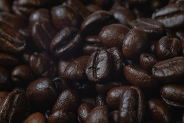 close up of pile roast coffee beans on wooden board