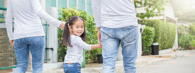 Portrait of little cute asian girl holding her father mother hands in the park. Together family’s...