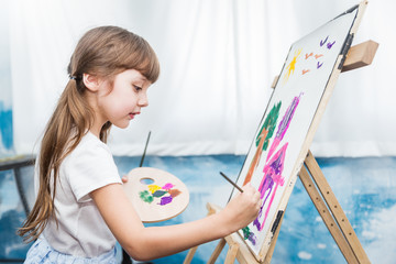 Portrait of cute little caucasian girl painting with watercolor in her art kindergarten classroom. Young creative gifted artist home school education learning doing activities back to school concept