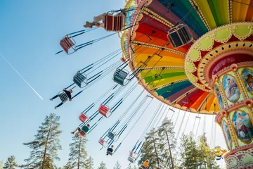 Foto auf Acrylglas Kouvola, Finnland - 18. Mai 2019: Ride Swing Carousel in Bewegung im Vergnügungspark Tykkimaki und Flugzeugspur im Himmel. © Elena Noeva
