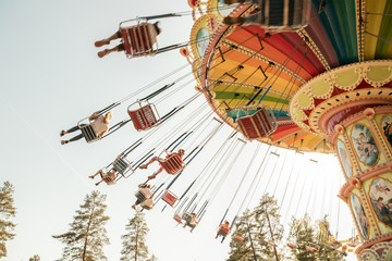 Kouvola, Finland - 18 May 2019: Ride Swing Carousel in motion in amusement park Tykkimaki and aircraft trail in sky.