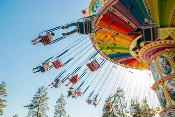 Foto auf Acrylglas Vergnügungspark Kouvola, Finnland - 18. Mai 2019: Ride Swing Carousel in Bewegung im Vergnügungspark Tykkimaki und Flugzeugspur im Himmel.