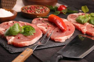 Raw pork meat steak with vegetables, peppers, tomato, salt, rosemary and spices cooking over stone table. Top view.