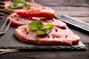 Raw pork meat steak with vegetables, peppers, tomato, salt, rosemary and spices cooking over stone table. Top view.