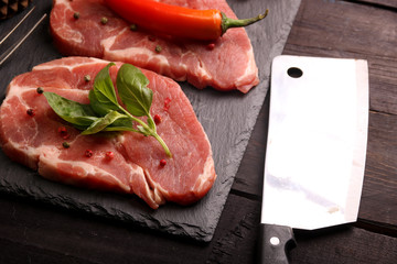 Raw pork meat steak with vegetables, peppers, tomato, salt, rosemary and spices cooking over stone table. Top view.
