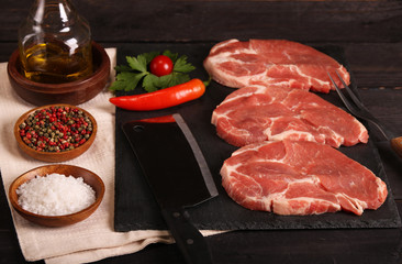 Raw pork meat steak with vegetables, peppers, tomato, salt, rosemary and spices cooking over stone table. Top view.
