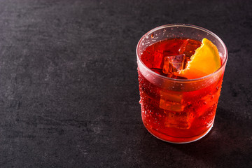 Negroni cocktail with piece of orange in glass on black background. Copyspace