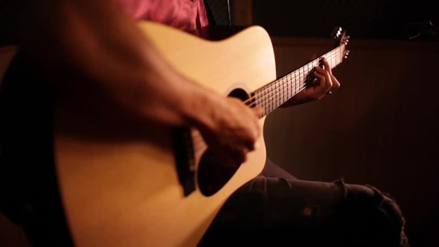 singer played the guitar in front of the microphone of a recording booth in a recording studio 