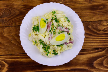 Salad with chinese cabbage, onion, sausage, eggs and mayonnaise on wooden table