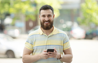 Handsome sporty bearded dark-haired man is using the phone.
