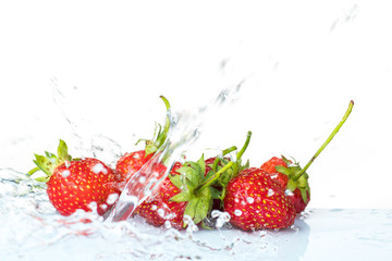 Several ripe wet red strawberries on white or colored background with splashes of water