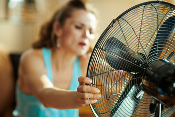 Closeup on housewife using fan suffering from summer heat