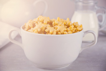 A bowl of dry star shaped cereal and a bottle of milk