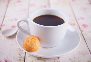 Cup of coffee with small balls of freshly baked homemade cottage cheese doughnuts in a plate on a background.