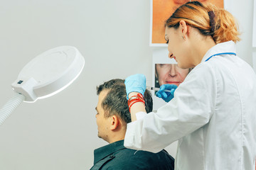 A young man with a bald spot in the office of a trichologist cosmetologist. Mesotherapy of hair and...