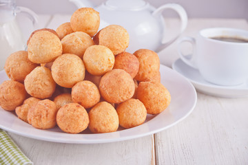 Small balls of freshly baked homemade cottage cheese doughnuts in a plate on a white background.