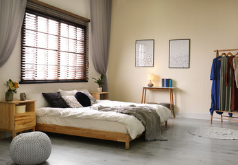 Modern room interior with comfortable double bed and window blinds