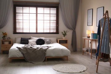 Modern room interior with comfortable double bed and window blinds