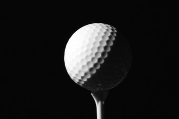 Golf ball on tee against dark background