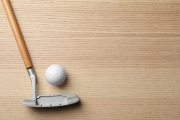Golf club and ball on wooden background, flat lay with space for text