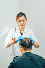 A young man with a bald spot in the office of a trichologist cosmetologist. Preparing for...