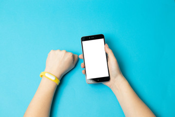Top view of female with tracker and mockup smart phone screen on blue background. Flat lay, top view