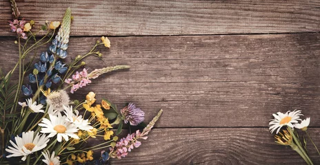 Fotobehang Wild flowers on old grunge wooden background (chamomile lupine dandelions thyme mint bells rape) © Chepko Danil