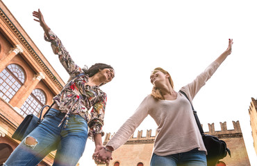 Happy multiracial girlfriends having genuine fun walking in city center - Friendship concept with girls at old town tour - Modern lifestyle with female friends cheering with hands up - Retro filter