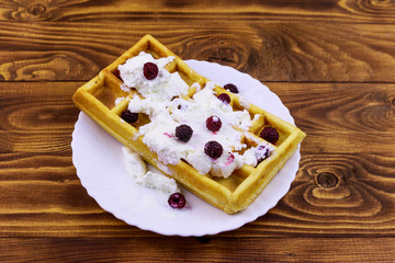 Belgian waffle with ice cream and blackberries on wooden table