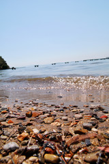 Exotic rocky beach with colorful stones, tropical blue sea with waves and foam. Beautiful natural environment, panorama, landscape. Idyllic seaside resort in summer season, paradise, amazing scene.