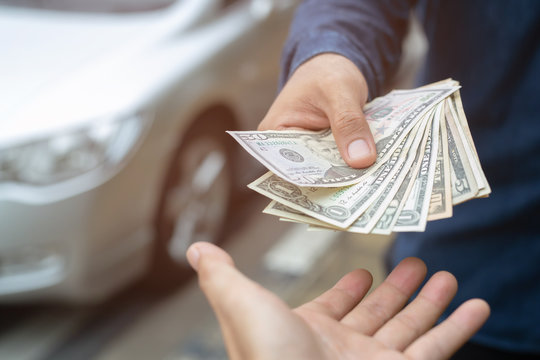 Business man holding money in hand stand front car prepare pay by installments - insurance, loan and buying car concept