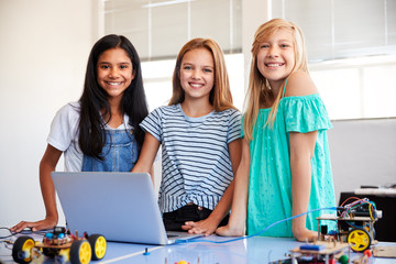 Portrait Of Three Female Students Building And Programing Robot Vehicle In School Computer Class