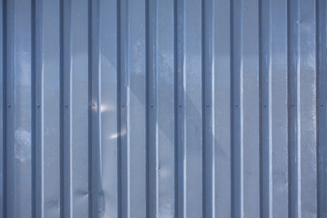 Close up photo of a facade from an industrial building with stripes of minimalistic weathered vertical metal profiles. Background image.