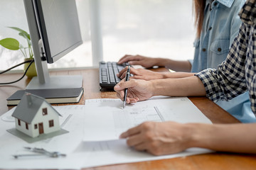 Engineers discuss a blueprint while checking information on a tablet computer in a office.