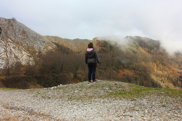 girl walks alone in the mist and fog along the paths of the Apuan Alps in Tuscany