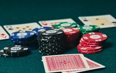 Close-up of two cards face down on the green mat to the right of the image to leave room for editing, other cards and poker chips are out of focus on the mat.