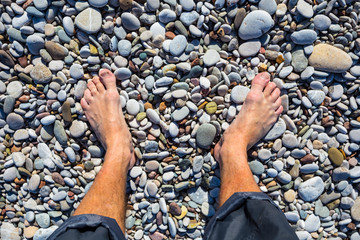 closeup people legs on the stony sea beach background
