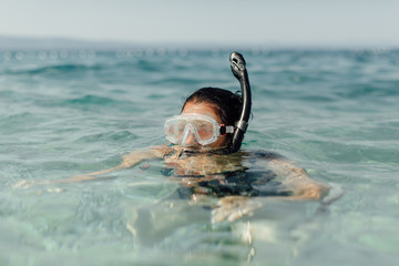 Female swimmer learning to snorkel. Snorkeling - woman wearing diving mask and snorkel swimming in...