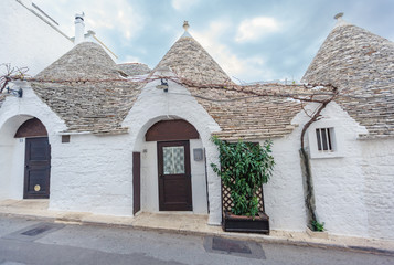 Beautiful town of Alberobello with Trulli houses among green plants and flowers, Apulia region, Southern Italy.