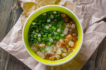 Chicken soup with green onion and croutons in bowl on wooden table